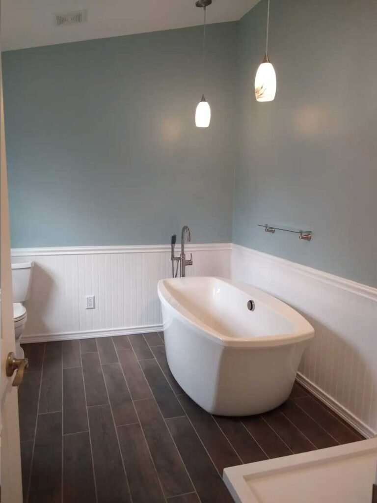 Freestanding bathtub with tiled bathroom floor. Wainscoting around perimeter of the bathroom.