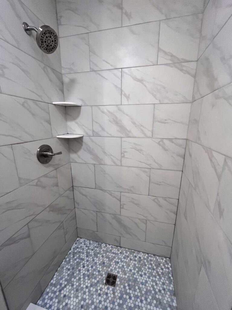 Tiled shower walls and base with quartz shelves.