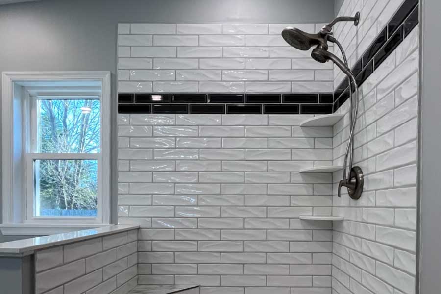 White Tiled shower with a black tile stripe.