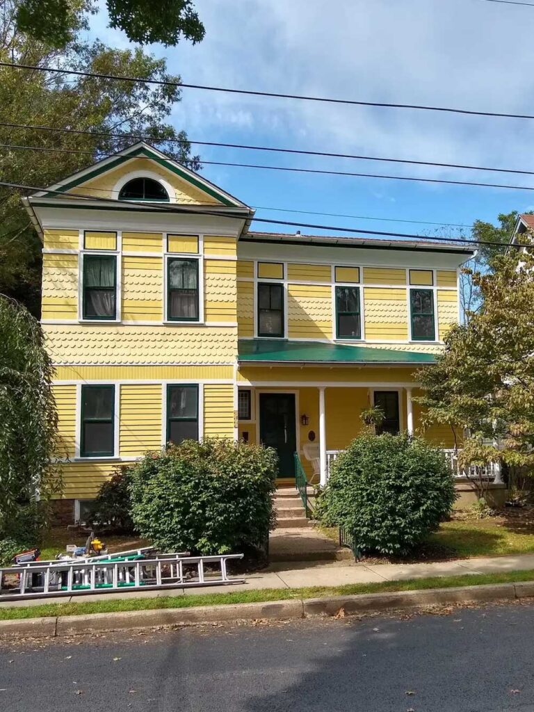 Exterior renovation of an old Victorian house. Painted yellow, white, and green