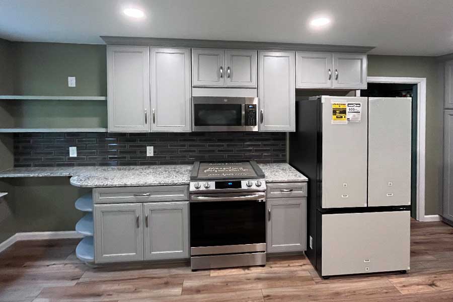 Kitchen with grey cabinets a tile backsplash and granite countertops