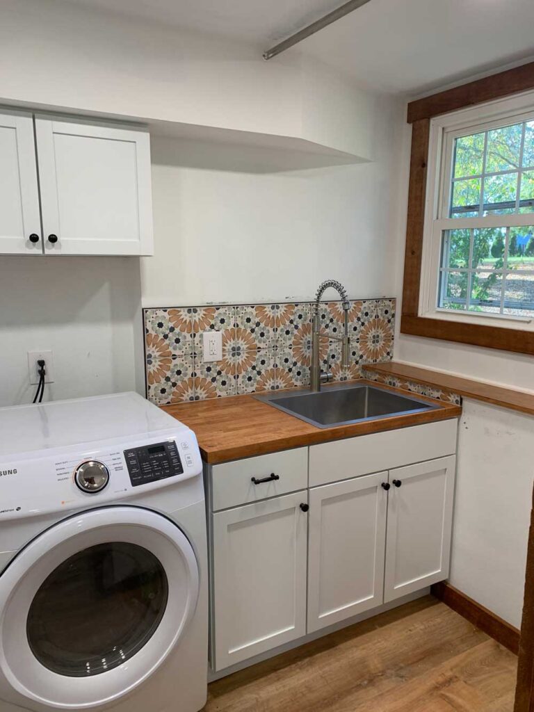 Laundry room sink with tiled backsplash and rough sawn wood trim.