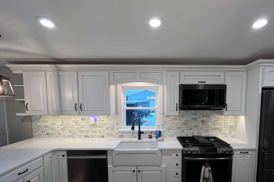 White kitchen with crown molding, a marble backsplash and a quartz countertop top