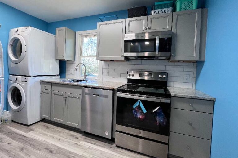 Kitchen with grey cabinets, LVP flooring, and a white tile backsplash