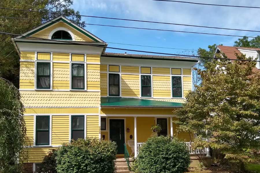 Exterior renovation of an old Victorian house. Painted yellow, white, and green